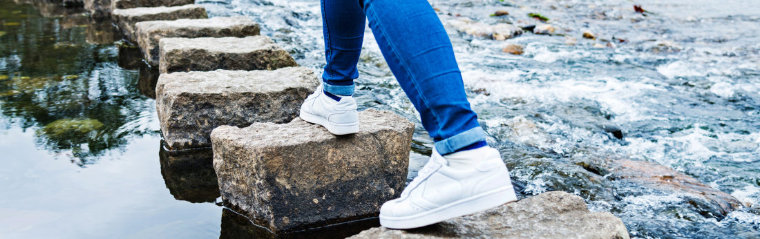 Füße gehen über Steine im Wasser (Bild: istock)