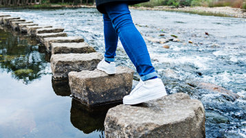 Füße gehen über Steine im Wasser (Bild: istock)