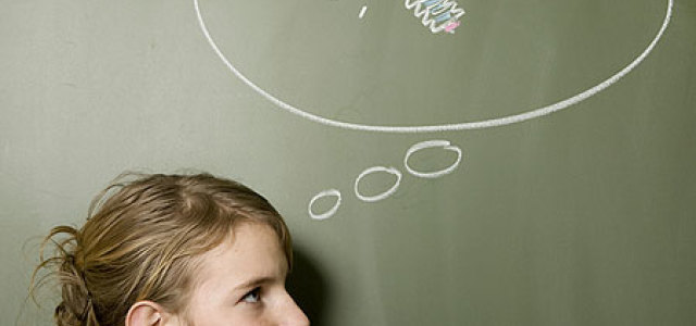 Eine junge Frau steht vor einer Tafel, auf der eine Glühbirne in einer Denkblase zu sehen ist und grübelt (Bild:iStock)