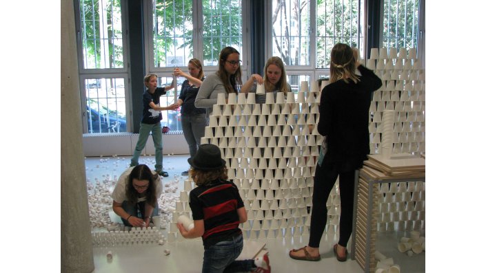 Kinder bauen eine Mauer aus Pappbechern