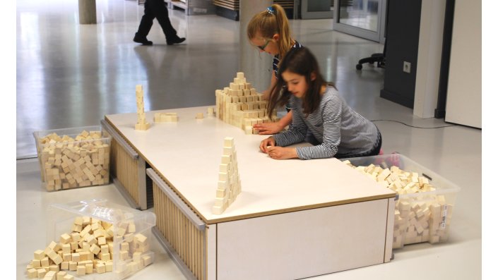 Kinder überlegen verschiedene Figuren mit Bausteinen und Materialien
