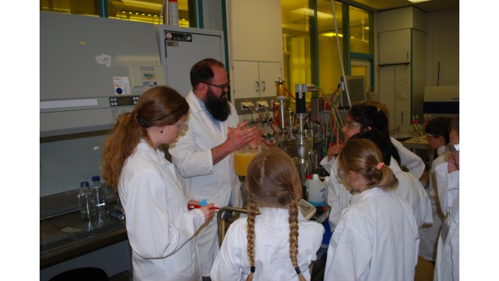 Kinder und Erwachsene in Schutzkleidung stehen in einem Chemielabor
