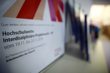 In einem Bilderrahmen wurde das offizielle Ankündigungsplakat am HIP-Handapparat in der Hochschulbibliothek am Campus Südstadt im Wintersemester 2018/19 gezeigt