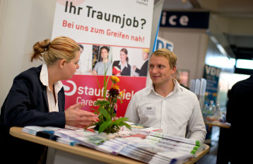 Eine Frau und ein Mann unterhalten sich an einem Messestand