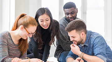 Das Foto zeigt eine Gruppe Studierender, die über einen Text gebeugt sind und sich unterhalten. Das Foto zeigt eine Gruppe Studierender, die über einen Text gebeugt sind und sich unterhalten.