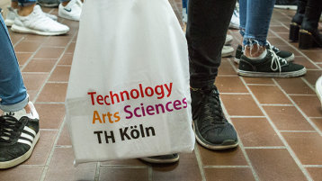 Füße und eine TH Köln-Stofftasche (Bild: Heike Fischer/TH Köln)
