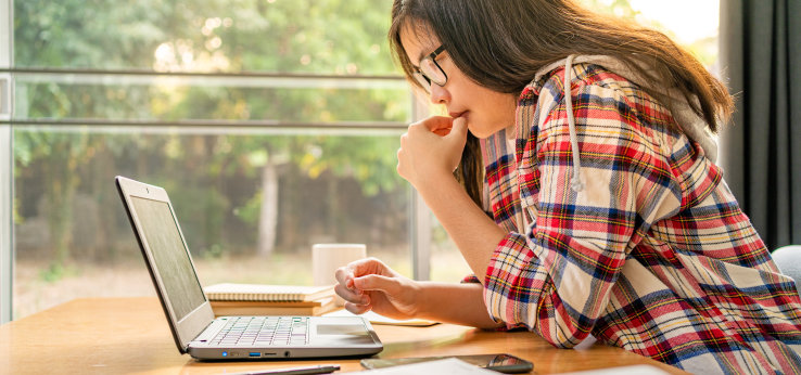 Studentin sitzt an einem Schreibtisch und schaut auf ihr Laptop (Bild: adobe stock)