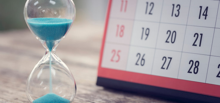 Sanduhr, im Hintergrund ein Kalender (Image: adobe stock)