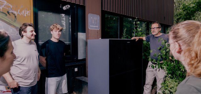 Studierende und Professor stehen draußen am Gebäude der TH Köln neben einer Wärmepumpe (Bild:Thilo Schmülgen/TH Köln)