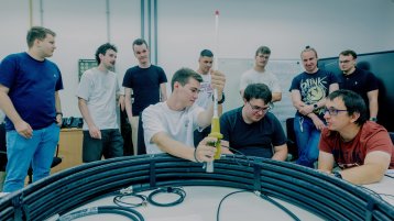 Neun männlich gelesende Studierende stehen mit dem Dozent um eine Antennenanlage in einem Raum der Hochschule (Bild: Thilo Schmülgen/TH Köln)