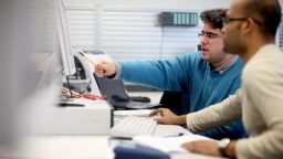 Ein Studierender zeigt einem anderen Studierenden etwas an einem Computer-Monitor