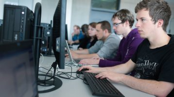 Studierende sitzen in einer Reihe an Computermonitoren (Bild: Thilo Schmülgen/FH Köln)