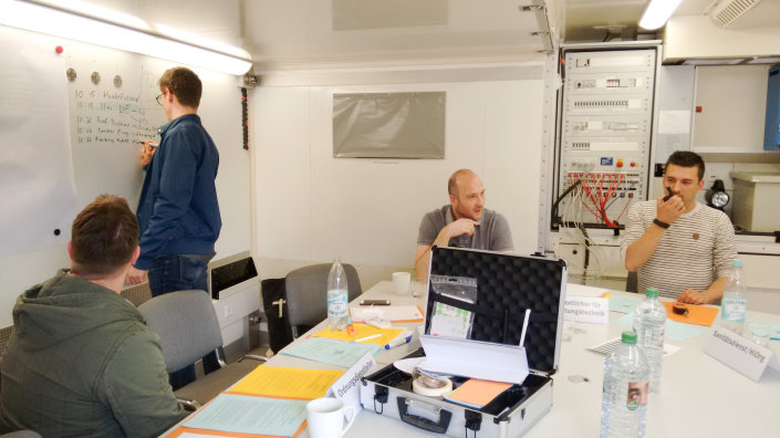 Die Leitungsgruppe hält eingehende Meldungen und ihre Reaktionen auf diese an einem Whiteboard fest.