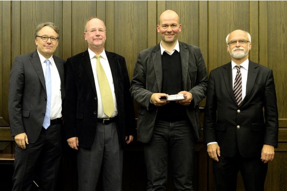 Gruppenfoto mit Professor Karl Maier, Professor Peter Schimikowski und Professor Jochen Axer mit einem Absolventen