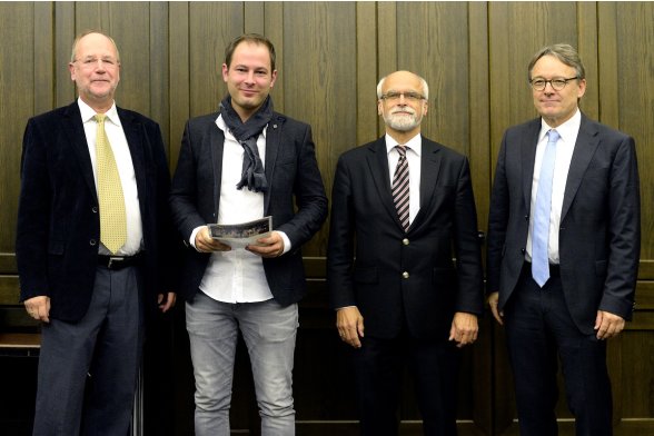 Gruppenfoto mit Professor Peter Schimikowski, Professor Jochen Axer und Professor Karl Maier mit einem Absolventen