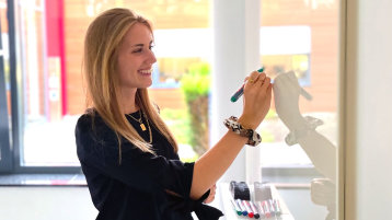 Campaign Managerin steht an einem Whiteboard und schreibt Brainstorming-Punkte auf die Tafel (Bild: Sarah Kern)