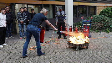 Eine Teilnehmende des Lehrgangs "Brandschutzbeauftragte:r" löscht einen Brand. (Bild: TH Köln)