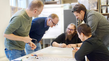 Eine Gruppe angehender kommunaler Verkehrsplaner:innen beugt sich über einen mit Plänen ausgelegten Tisch. (Bild: TH Köln)