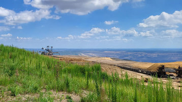 Blick auf den Tagebau Hambach. Im Kontrast dazu hebt sich im Vordergrund knallig grünes Gras der renaturierten Sophienhöhe ab. (Bild: TH Köln)