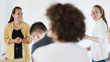 Zwei junge Frauen präsentieren lachend ihre Ideen vor dem Plenum. (Bild: TH Köln)