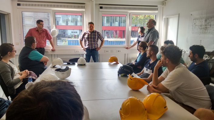 Projektsteuerer Clemens Raus (hinten links) und Lutz Krüger briefen die angehenden Fachplaner*innen und Fachbauleiter*innen im Brandschutz Projektsteuerer Clemens Raus (hinten links) und Lutz Krüger briefen die angehenden Fachplaner*innen und Fachbauleiter*innen im Brandschutz