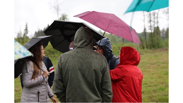 Die Gruppe steht im Regen unter Regenschirme geduckt.