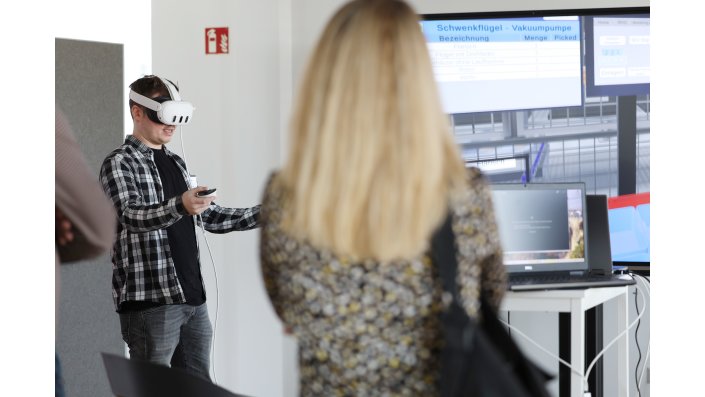 Ein junger Mann mit VR-Brille führt die Navigation in der VR-Welt der virtuellen Fabrik vor.