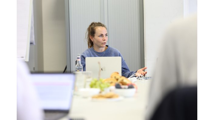 Weiterbildungsentwicklerin Julia Gerber sitzt vor ihrem Laptop und präsentiert den aktuellen Stand in der Runde.