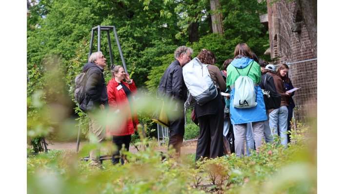 Die Teilnehmenden arbeiten im Park stehend auf Arbeitsblättern.