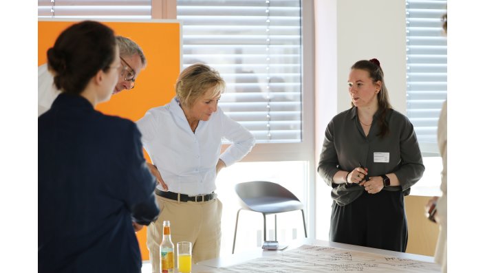 An einem weiteren Tisch ist eine andere Personengruppe im Gespräch.