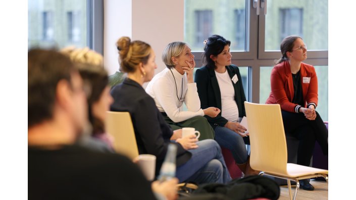 Die Teilnehmenden sitzen auf Stühlen und Sitzwürfeln locker beisammen.