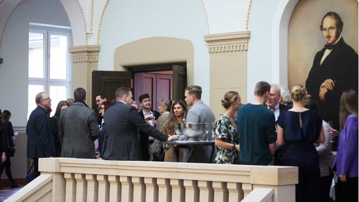 Teilnehmende der Absolvent:innen-Feier des Masterstudiengangs Versicherungsrecht LL.M. an der TH Köln beim geselligen Umtrunk im historischen Treppenhaus der Claudiusstraße 1.