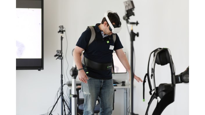 Ein Besucher auf dem VR-Laufband schaut in Richtung Boden, wo sich in der VR-Welt Wasser befindet.