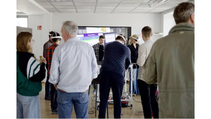 Eine Gruppe Besuchender nimmt am Workshop zur virtuellen Fabrik teil. Vier von ihnen tragen eine VR-Brille.