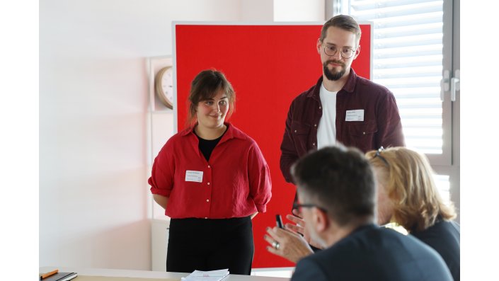 Zwei Entwickler:innen des Projektteams lauschen den Ausführungen eines Beiratsmitglieds an ihrem World-Café-Tisch.