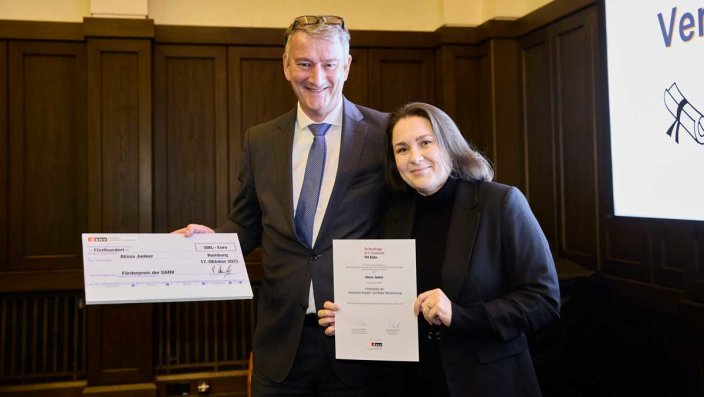 Peter Dümpelmann von der Deutschen Anwalt- und Notar-Versicherung (DANV) überreicht Absolventin Alissa Junker bei der Abschlussfeier des Masterstudiengangs Versicherungsrecht LL.M. an der TH Köln den DANV-Förderpreis.