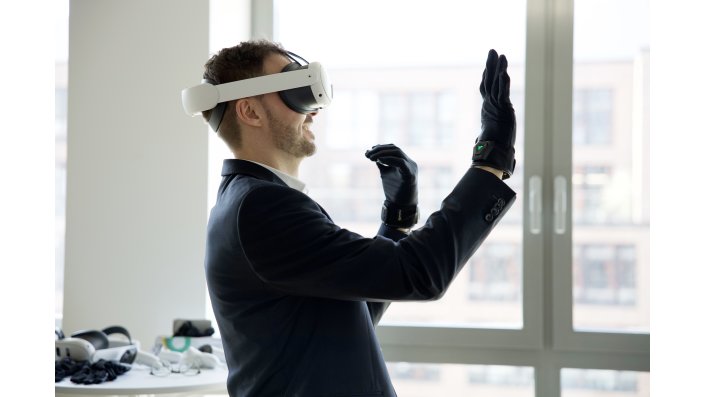 Ein Mann im Profil streckt lachend die Hand im VR-Handschuh aus.