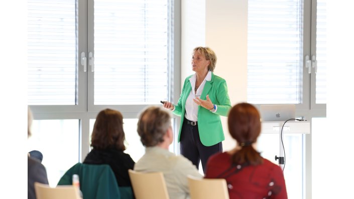 Elke Hohmann steht vor den Anwesenden und hält ihren Impulsvortrag.