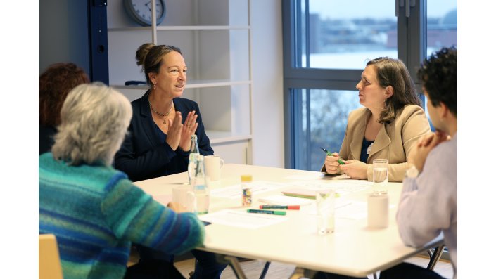 Eine Arbeitsgruppe sitzt diskutierend an einem Tisch zusammen.