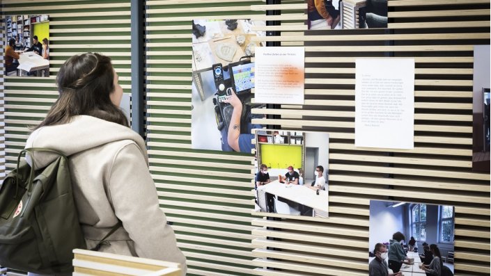 eine Frau schaut sich Fotos an, die an einer Wand hängen